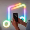 A person is holding a smartphone and interacting with a music note-shaped LED light display on a wall. Produktbild-Vorschau