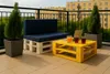 A balcony setting with a pallet sofa and coffee table, drinks, and plants. Anteprima dell’immagine prodotto