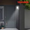 A modern front door with a Telefunken LED outdoor light mounted on the wall next to it. Produktbild-Vorschau
