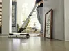A person is using a Kärcher FC 7 Cordless Premium floor cleaner in a modern living room. Produktbild-Vorschau