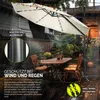 An outdoor patio scene with a large cantilever umbrella providing shade over a table and chairs, with rain effects and text overlays highlighting product features. Náhľad obrázku produktu