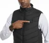 A man wearing a black heated vest over a white shirt, pointing to a button on the vest. Náhľad obrázku produktu