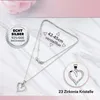A silver heart-shaped pendant necklace with clear crystals, displayed on a marble-like surface with a soft pink floral element in the background. Text overlays provide product details. Produktbild-Vorschau