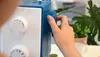 A close-up shot of a person's hand adjusting a dial on a sewing machine. Produktbild-Vorschau