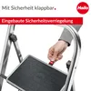 A close-up of a person's hand operating a safety lock on a step stool. Náhled obrázku produktu
