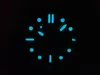 A close-up of a watch face in the dark, with luminous markers and hands. Podgląd zdjęcia produktu
