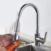 A person is washing a carrot under a flexible faucet extender in a kitchen sink. Produktbild-Vorschau