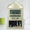 A digital Islamic clock with a mosque-like dome design, displaying prayer times, date, and temperature, placed on a surface next to a green mug. Produktbild-Vorschau