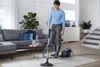 A woman is vacuuming a living room with a Philips vacuum cleaner. Produktbild-Vorschau