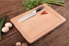 A wooden cutting board with a knife, chili peppers, eggs, cucumber, and asparagus on a wooden table. Produktbild-Vorschau
