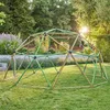 A geodesic dome climbing frame is set up on a grassy lawn in a garden, with trees and bushes in the background. Produktbild-Vorschau
