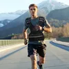 A man is running on a road with mountains in the background, wearing a weighted vest. Náhled obrázku produktu