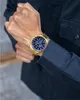 A person wearing a dark blue shirt and a gold Maserati watch on their wrist. Produktbild-Vorschau