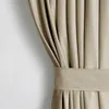 A close-up view of a beige velvet curtain with pleats and a tie-back. Produktbild-Vorschau