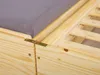 Close-up view of a wooden bed frame with a gray mattress. Produktbild-Vorschau