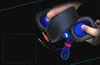 Hands holding a pair of black over-ear headphones with blue mesh accents and red and black audio jacks. Produktbild-Vorschau