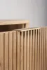 Close-up of a wooden cabinet with a fluted front and a gold handle. Produktbild-Vorschau