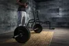 A person in a gym setting with weightlifting equipment. Náhľad obrázku produktu
