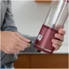 A person is plugging a USB cable into a portable blender. Podgląd zdjęcia produktu