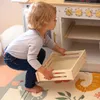 A young child is playing with a toy kitchen, placing a wooden crate into the oven. Náhľad obrázku produktu