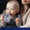 A baby is being held by an adult and drinking from a sippy cup. Produktbild-Vorschau
