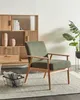 A green upholstered armchair with light brown wooden armrests and legs is placed on a rug in front of a wooden bookshelf. Náhled obrázku produktu