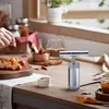 A kitchen counter with food preparation items, including a metal pollen press. Produktbild-Vorschau