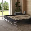 A sofa bed with its mattress frame extended, set in a room with a large window and wooden wall paneling. Produktbild-Vorschau