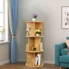 A rotating bookshelf filled with decorative items and books, placed in a room with blue curtains and a sofa. Produktbild-Vorschau