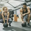 A man and a woman are in a gym setting, both in workout attire and holding slam balls. Produktbild-Vorschau