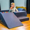 A young child is playing with colorful balls in a soft play area. Produktbild-Vorschau