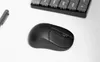 A black wireless mouse and a portion of a keyboard are shown on a white surface. Produktbild-Vorschau