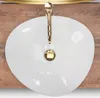 A top-down view of a white oval sink with a gold faucet, set against a wooden background. Náhled obrázku produktu