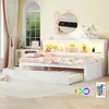 A white daybed with a pull-out trundle bed, featuring LED lighting and a built-in charging station. The room is decorated with pink accents and toys, suggesting a child's bedroom. Podgląd zdjęcia produktu