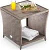 A wicker side table with a magazine and a glass of orange juice on top, and a folded towel on the shelf below. Produktbild-Vorschau