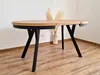 A round dining table with black metal legs is shown in a room with wooden floors and a white wall. Produktbild-Vorschau