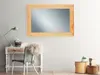 A mirror is mounted on a wall above a desk with a chair and some decorative items. Produktbild-Vorschau