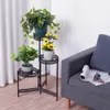 A plant stand with three tiers holding potted plants, placed next to a sofa in a living room. Náhľad obrázku produktu