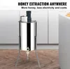 A stainless steel honey extractor is shown in a kitchen setting with cabinets in the background. Náhled obrázku produktu