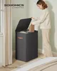 A woman is placing laundry into a two-compartment hamper in a bedroom setting. Podgląd zdjęcia produktu