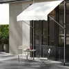 An outdoor cafe setting with a white awning over a doorway, a small round table with two chairs, and a potted plant. Produktbild-Vorschau