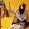 A young woman wearing a puffer jacket and hoodie, holding a yellow smartwatch tracker. Voir les images du produit