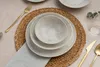 A table setting with plates, a bowl, cutlery, and a napkin on a woven placemat. Náhľad obrázku produktu