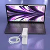 A laptop and its charger are displayed on a purple surface. Podgląd zdjęcia produktu