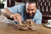 A man is assembling a wooden model motorcycle on a table. Anteprima dell’immagine prodotto