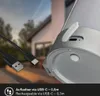 Close-up of a rechargeable LED table lamp with a USB-C charging cable and port visible, set against a blurred background of a house and trees. Anteprima dell’immagine prodotto