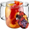 Three glass jars, one filled with colorful bell pepper slices and the others empty. A decorative lid with fruit imagery is in the foreground. Anteprima dell’immagine prodotto