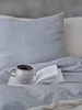 A cozy scene with a book and a mug on a bed. Produktbild-Vorschau