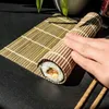 A hand is shown rolling a sushi roll on a bamboo mat. Náhľad obrázku produktu