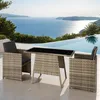 A rattan dining set for two is placed on a patio overlooking a scenic ocean view with an infinity pool. Voir les images du produit